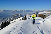 Female backcountry skier ascending to Brennkopf, Mangfall mountains in background, Chiemgau Alps, Tyrol, Austria