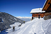 Gruppe von Skitourengehern gehen auf verschneite Almhütten zu, Hoher Kopf, Tuxer Alpen, Tirol, Österreich