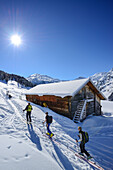 Gruppe von Skitourengehern gehen an verschneiter Almhütte vorbei, Hoher Kopf, Tuxer Alpen, Tirol, Österreich
