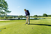 Golfspieler beim Putten auf dem Grün, Schleswig-Holstein, Deutschland