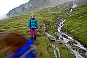 Two female hikers walking beside a stream, Nockberge, Carinthia, Austria