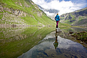 Junge Frau steht auf einem Stein im Fluss Soca, Alpe-Adria-Trail, Tolmin, Slowenien
