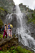 Two female hikers looking at a waterfall, Nockberge, Carinthia, Austria