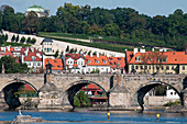 View to Prague's famous Charles Bridge over the Vltava river, with vineyards of the Letna Parks visible in the background, Prague, Czech Republic, Europe
