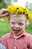 Junge (2 Jahre) mit einem Blumenkranz auf dem Kopf, Feldberger Seenlandschaft, Mecklenburg-Vorpommern, Deutschland