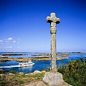 Cruise boat passing ´La Croix de Maudez´ cross 18th Century ´Bréhat´ island Brittany France