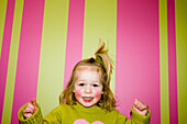 Little Girl Smiling in front of Striped Wall