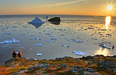 Couple looking out at an Iceberg at Sunset, Twillingate, Newfoundland