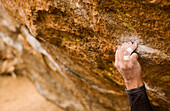 Mans Hand Clinging to Rock while Climbing