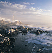 Fog and Rocky Shoreline in Winter with Cap des Rosiers Lighthouse, Northeast GaspÄ Peninsula, near mouth of St. Lawrence River, Quebec