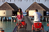 Republic of the Maldives, Lhaviyani Atoll,  Kanuhura Hotel, landing stage and two persons riding tricycles