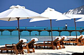 Republic of the Maldives, Lhaviyani Atoll,  Kanuhura Hotel, Deckchairs under beach umbrellas, Landing stage with a man and his bicylce in the background