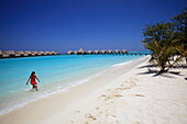 Republic of the Maldives, Lhaviyani Atoll,  Kanuhura Hotel, Woman paddling on the beach