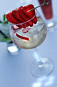 Red Fruit Cocktail with slices of strawberries on a small stick
