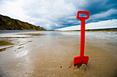 Red Plastic Spade In Sand On Beach