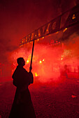 Silhoutte Of Man From Southover Bonfire Society With 'advance' Banner In Front Of Red Flares At 'bonfire Prayers' At End Of Bonfire Night, Lewes, East Sussex, Uk