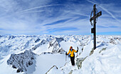 Frau steht am Gipfelkreuz der Ruderhofspitze, Stubaier Alpen, Tirol, Österreich