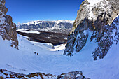 Two backcountry skiers ascending through cirque to Monte Pesco Falcone, Rava del Ferro, Maiella, Abruzzo, Italy