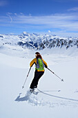 Female backcountry skier downhill skiing, Vallatscha, Sesvenna range, Ortler in background, Ofenpass, Grisons, Switzerland