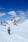 Female backcountry skier ascending to Monte Cevedale, Koenigspitze, Suldenspitze and Rifugio Casati in background, Ortler range, South Tyrol, Italy