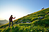 Frau steigt über eine Wiese zur Kampenwand auf, Chiemgauer Alpen, Chiemgau, Oberbayern, Bayern, Deutschland