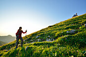 Woman ascending over meadow to Kampenwand, Chiemgau Alps, Chiemgau, Upper Bavaria, Bavaria, Germany