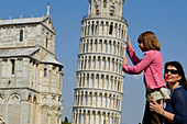 Frau mit Kind stützen den Schiefen Turm von Pisa, Toskana, Italien