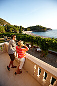 Paar betrachtet Aussicht vom Balkon der Villa Milocer, Aman Sveti Stefan, Sveti Stefan, Budva, Montenegro