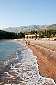 Couple at beach, Villa Milocer in background, Aman Sveti Stefan, Sveti Stefan, Budva, Montenegro