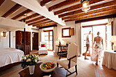 Paar in einer Hotelsuite mit Deckenbalken und Mobiliar im mallorquinischen Stil, Hotel La Residencia, Deia, Mallorca, Spanien