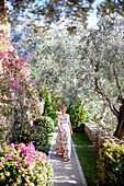 Woman walking through a garden of hotel, Deia, Majorca, Spain