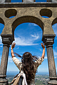 Woman with arms raised, looking through an opening at the Palacio Nacional da Pena (Pena National Palace), Sintra, Estremadura, Portugal