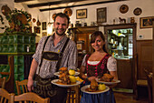 Friendly waiter and waitress serving plates of pork with dumplings, Schaeufele in Boehm's Herrenkeller restaurant, Nuremberg, Franconia, Bavaria, Germany
