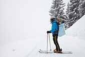 Skifahrer trägt Sohn auf dem Rücken, Lenggries, Brauneck, Bayern, Deutschland