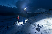 Junges Paar wandert über verschneite Highlands, Wester Ross, Torridon, Schottland, Großbritannien