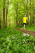 Young man jogging in beech forest, National Park Hainich, Thuringia, Germany