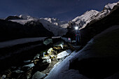 Hiker with headlamp in Morteratsch valley, Piz Palu, Piz Bernina and Piz Zupo in background, Engadin, Canton of Grisons, Switzerland