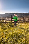Young woman hiking across a vineyard, Val d Orcia, Tuscany, Italy