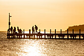 Leute auf einem Steg am Lake King im Sonnenuntergang, Metung, Victoria, Australien