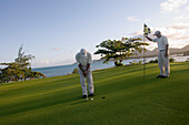 Zwei Golfspieler auf dem Grün von Loch 11 Round the Bend auf dem Le Touessrok Golf Course, nahe Trou d'Eau Douce, Flacq District, Mauritius, Indischer Ozean