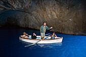 Mann singt ein Ständchen für drei Touristen in einem Ruderboot in der Blauen Grotte von Capri, Kampanien, Italien, Europa
