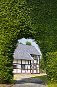 Half-timbered house behind a gate in a hedge of beeches, Monschau-Hoefen, Eifelsteig hiking trail, Eifel, North Rhine-Westphalia, Germany