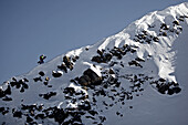 Junger Snowboarder läuft auf den Gipfel eines Berges, Pitztal, Tirol, Österreich
