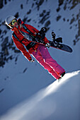 Junge Snowboarderin steigt durch Tiefschnee in den Bergen, Pitztal, Tirol, Österreich
