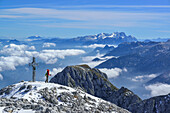 Frau am Gipfelkreuz des Hoher Göll, Dachstein im Hintergrund, Nationalpark Berchtesgaden, Berchtesgadener Alpen, Oberbayern, Bayern, Deutschland