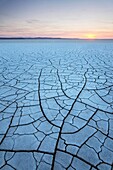 Setting sun on patterns of cracked mud on dry lakebed of Harney Lake, Malheur National Wildlife Refuge, Oregon