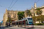 Modern tram against The Cathedral of Saint Mary of the See, Catedral de Santa Maria de la Sede,Seville Cathedral, Avenida de la Constitucion, Seville, Sevilla, Andalusia, Spain
