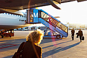 Businessmen and travelers board a plane on the tarmac at sunset