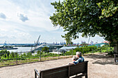 Couple sitting on a bench on the Altona terraces, looking towards Hamburg harbour, Hamburg, Germany