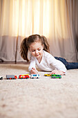Girl Playing on Floor with Miniature Cars and Trucks